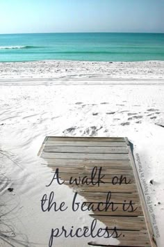 a wooden dock sitting on top of a sandy beach next to the ocean with waves coming in