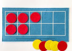 a felt board with four red and yellow circles next to it on a white surface