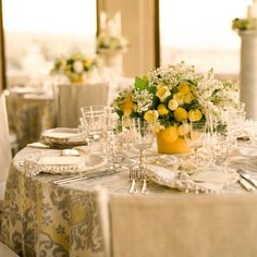 the table is set with yellow and white flowers