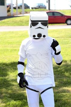 a man in a storm trooper costume is standing on the grass with his hands in his pockets