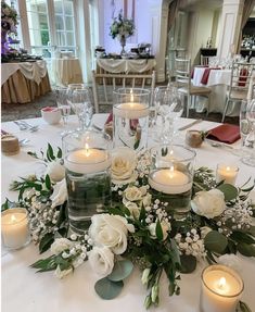 the table is set with candles, flowers and greenery for an elegant wedding reception