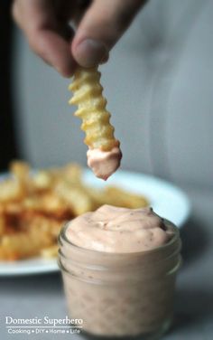 a person dipping some kind of sauce on top of food in a small glass jar