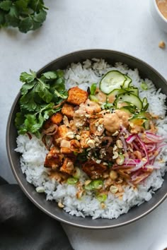 a bowl filled with rice, meat and veggies on top of a table