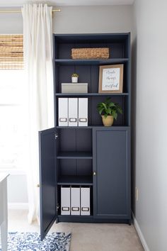 a blue bookcase with white file folders on it in front of a window