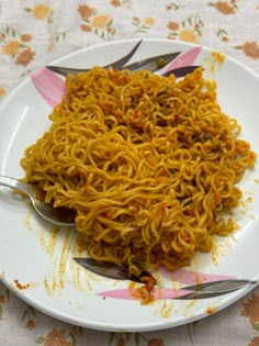 a white plate topped with noodles on top of a floral tablecloth covered table cloth