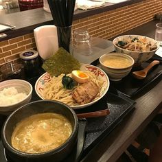 a table topped with bowls of food next to a counter filled with plates of food