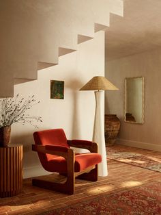 an orange chair sitting in front of a lamp on top of a wooden table