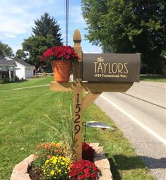 a mailbox with flowers in it and the words taylors on it is next to a flower bed