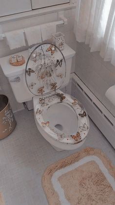 a white toilet sitting in a bathroom next to a rug and sink with the lid up