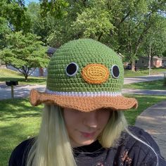 a woman wearing a crocheted hat with an orange and white eye patch on it