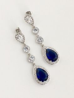 Long luxury blue sapphire cubic zirconia bridal tear dangle earrings in rhodium plated brass setting. Earrings feature a large teardrop with pear cut blue sapphire cubic zirconia center surrounded by tiny round zirconia crystals. Teardrop dangles from a bright cubic zirconia ear stud and two round cubic zirconia connectors. Total length of the earring is 6 cms. For matching necklace click: https://www.etsy.com/listing/252994446/long-blue-sapphire-cubic-zirconia-bridal?ref=shop_home_active_22 For Blue Teardrop Chandelier Earrings For Anniversary, Elegant Blue Cubic Zirconia Chandelier Earrings, Blue Cubic Zirconia Teardrop Earrings For Wedding, Blue Cubic Zirconia Crystal Earrings For Wedding, Blue Cubic Zirconia Crystal Earrings, Sapphire Pear-shaped Earrings For Wedding, Blue Cubic Zirconia Chandelier Earrings, Blue Cubic Zirconia Dangle Chandelier Earrings, Blue Cubic Zirconia Teardrop Earrings