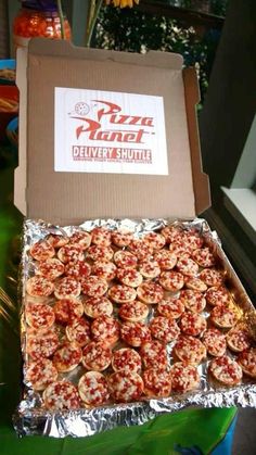 a box filled with mini pizzas sitting on top of a green table next to a window