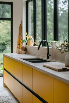 a kitchen with yellow cabinetry and large windows overlooking the trees outside in the day time