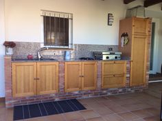 a kitchen with wooden cabinets and tile flooring next to a brick counter top oven