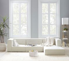 a living room with white furniture and large windows