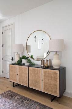 a living room with a large round mirror on the wall next to a wooden dresser