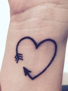 a heart with an arrow tattoo on the wrist