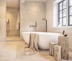 a bathroom with a large bathtub and wooden stumps on the floor next to it