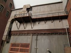 an old building with some metal doors and railings on the top floor, next to a fire hydrant