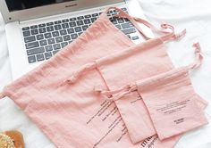 a laptop computer sitting on top of a white bed next to pink linen napkins