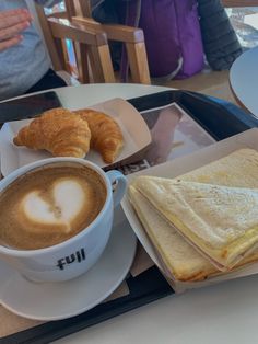 a cup of coffee, croissant and pastry on a tray