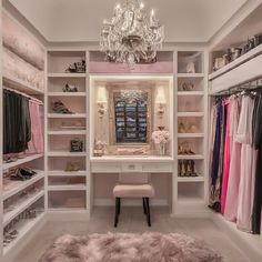 a walk in closet with a chandelier and dressing table