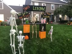 halloween decorations in front of a house with skeletons on the lawn and signs that say lemonade