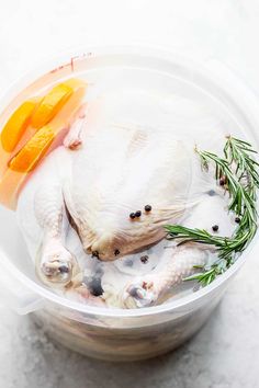 a plastic bowl filled with chicken, carrots and other food on top of a table