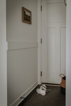 a pair of baby shoes sitting on the floor in front of a door with a basket