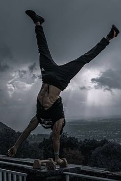 a man doing a handstand on top of a railing