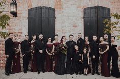 a group of people standing next to each other in front of a brick building with black shutters