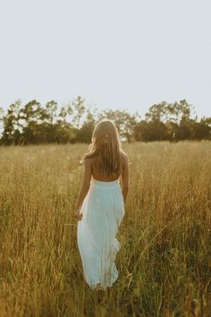 a woman in a white dress standing in tall grass