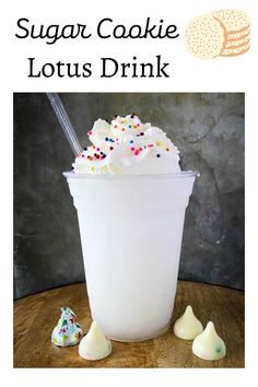 a white cup filled with whipped cream and sprinkles on top of a wooden table