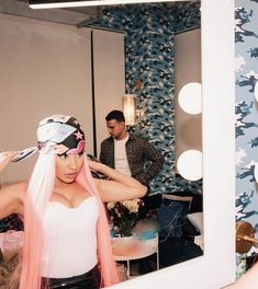 a woman with pink hair standing in front of a mirror