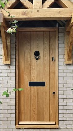 a wooden door with an arch above it in front of a white brick wall and green plants