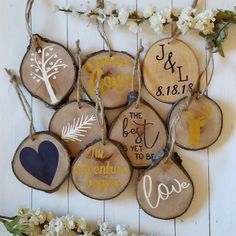 wood slice ornaments with names and date displayed on white wooden planked wall next to flowers