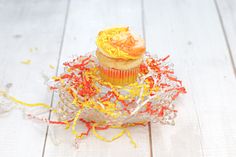 a cupcake with orange frosting and sprinkles