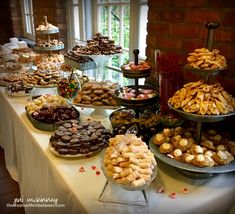 a table topped with lots of desserts and pastries on top of it's sides