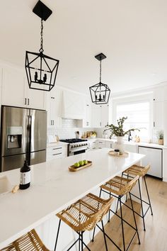 a kitchen with white counter tops and wooden stools next to an island in the middle