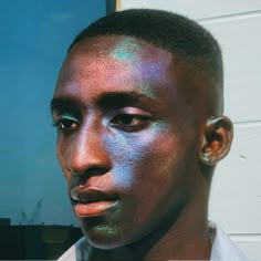 a close up of a person with blue paint on his face and shirt collared