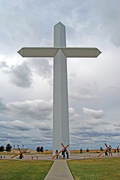 a large white cross sitting on top of a lush green field