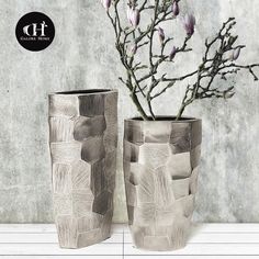 two vases sitting next to each other on a table with flowers in them,