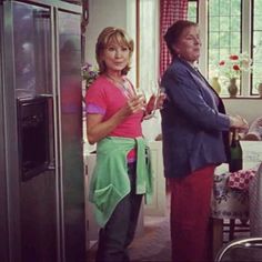 two women standing in a kitchen next to a refrigerator