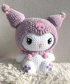 a crocheted stuffed animal sitting on top of a fluffy white blanket next to a wall