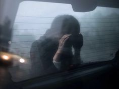 a woman sitting in the passenger seat of a car talking on her cell phone while looking out the window