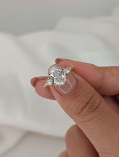 a woman's hand holding an engagement ring with three diamonds on it and the middle finger