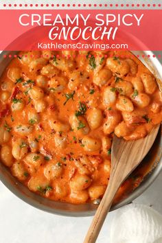 creamy spicy gnocchini in a pan with a wooden spoon on the side