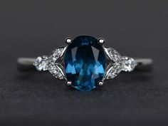 an oval cut blue topazte and diamond ring on a black surface with diamonds around it