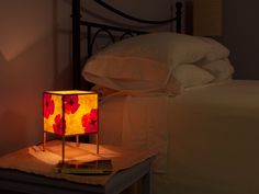 a lamp that is sitting on top of a table next to a bed with white sheets