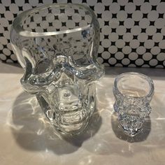 a clear glass vase with a skull design on it and another one sitting next to it